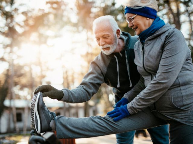 An older married couple enjoys exercising and jogging on a beautiful sunny winter day.