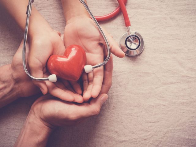 child and adult holding red heart with stethoscope, heart health,  health insurance concept