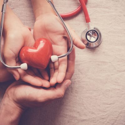 child and adult holding red heart with stethoscope, heart health