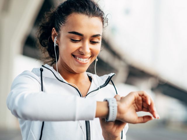 Smiling woman checking her physical activity on smartwatch. Youn