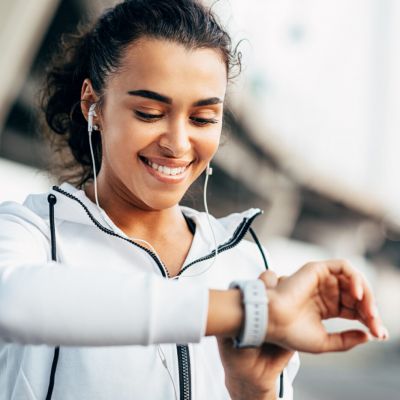 Smiling woman checking her physical activity on smartwatch. Youn