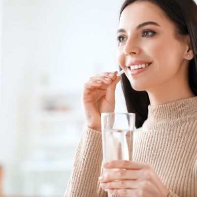 Beautiful young woman taking pills at home