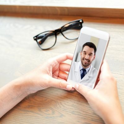 hands of woman holding phone with doctor on screen