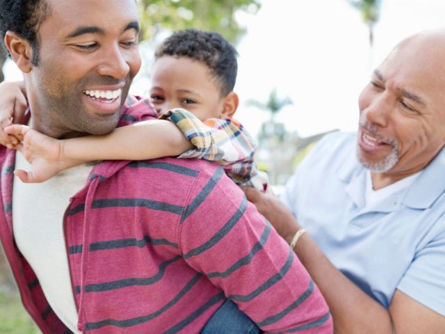 Little boy enjoying piggyback ride with father and grandfather