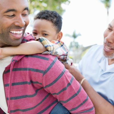 Little boy enjoying piggyback ride with father and grandfather