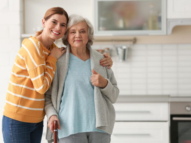 Elderly woman with female caregiver in kitchen. Space for text