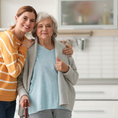 Elderly woman with female caregiver in kitchen. Space for text