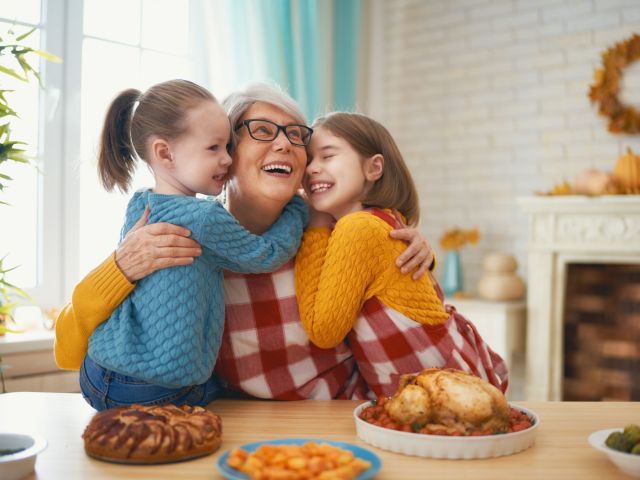 Happy Thanksgiving Day! Autumn feast. Family sitting at the table and celebrating holiday. Traditional dinner. Grandmother and granddaughters.