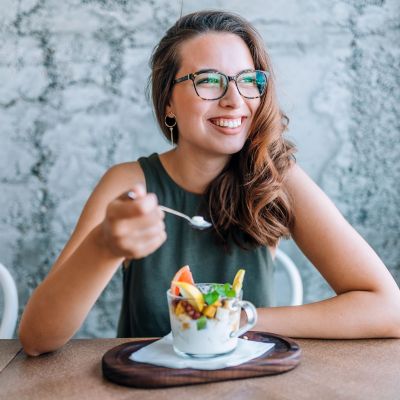 Young cheerful woman eating fruit salad.